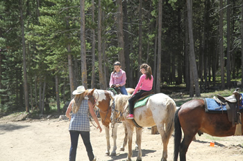 Children receiving horseback instructions from a staff member